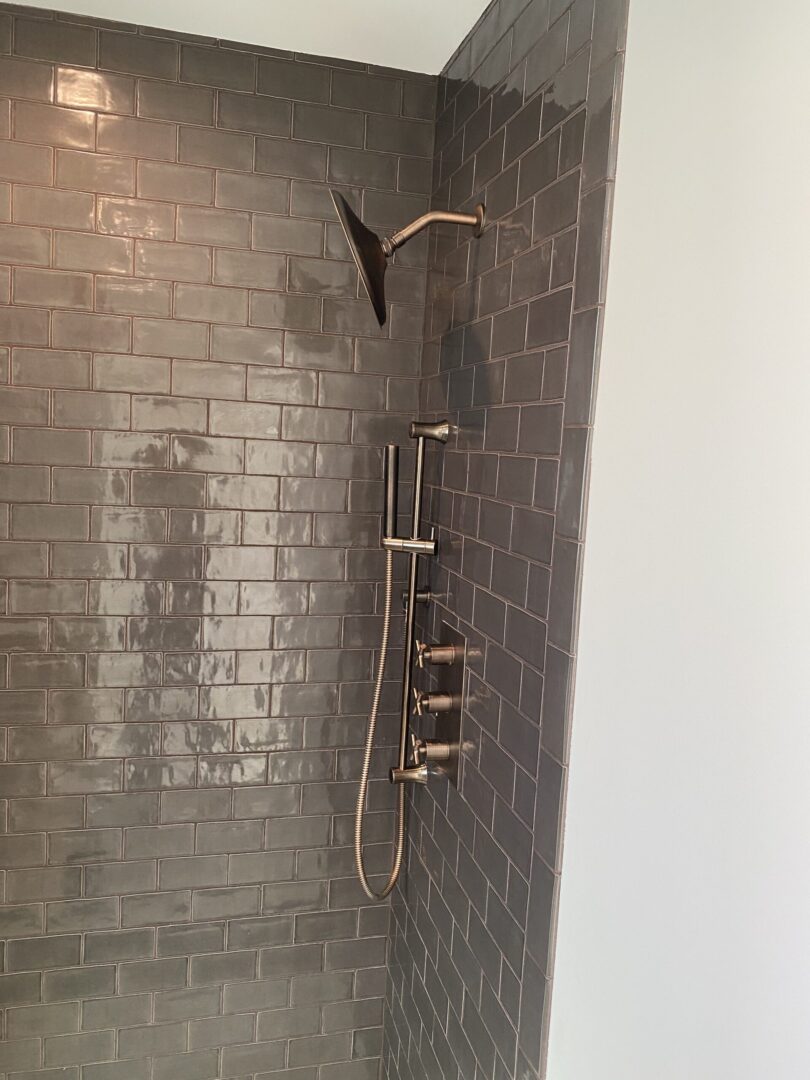 Hand shower mounted on the brown-colored tile wall