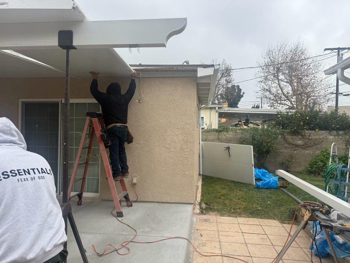 Worker installing exterior home features on ladder.